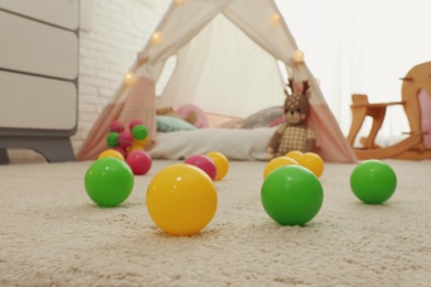 Photo of Bright toy balls near play tent on floor in child's room