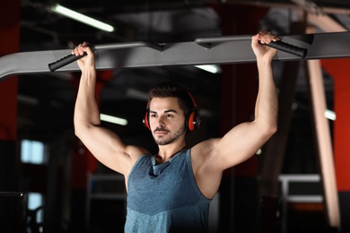 Young man with headphones listening to music and working out at gym