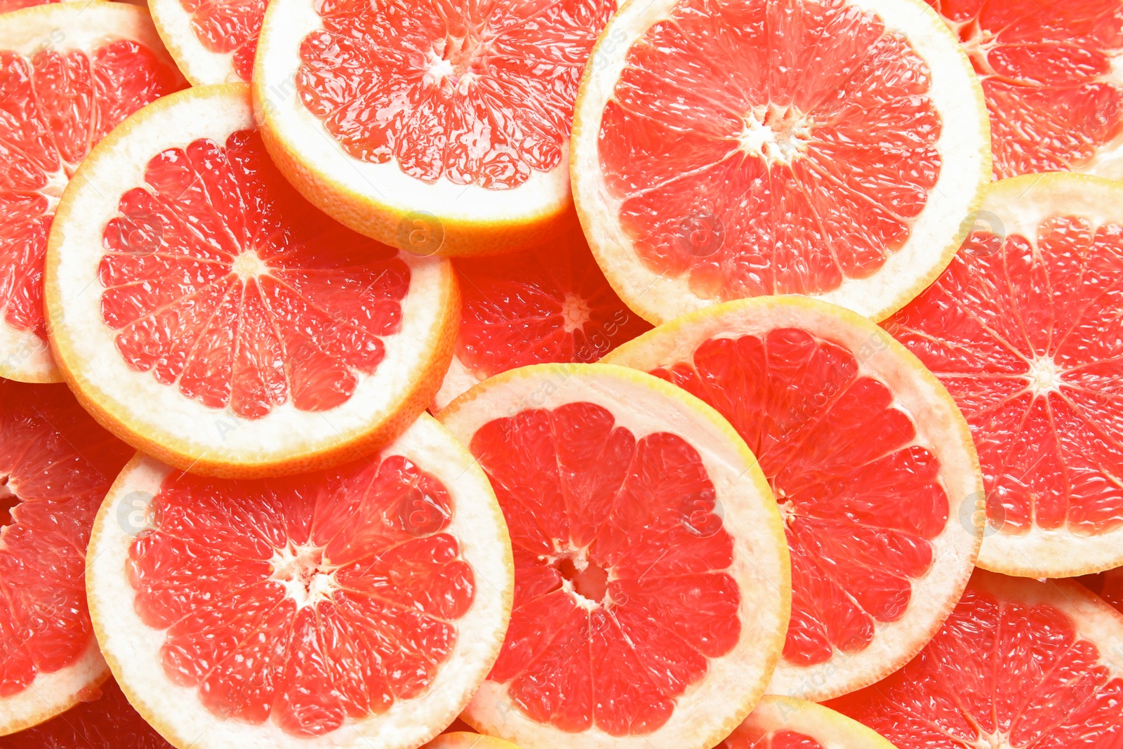 Photo of Many sliced fresh grapefruits as background, top view