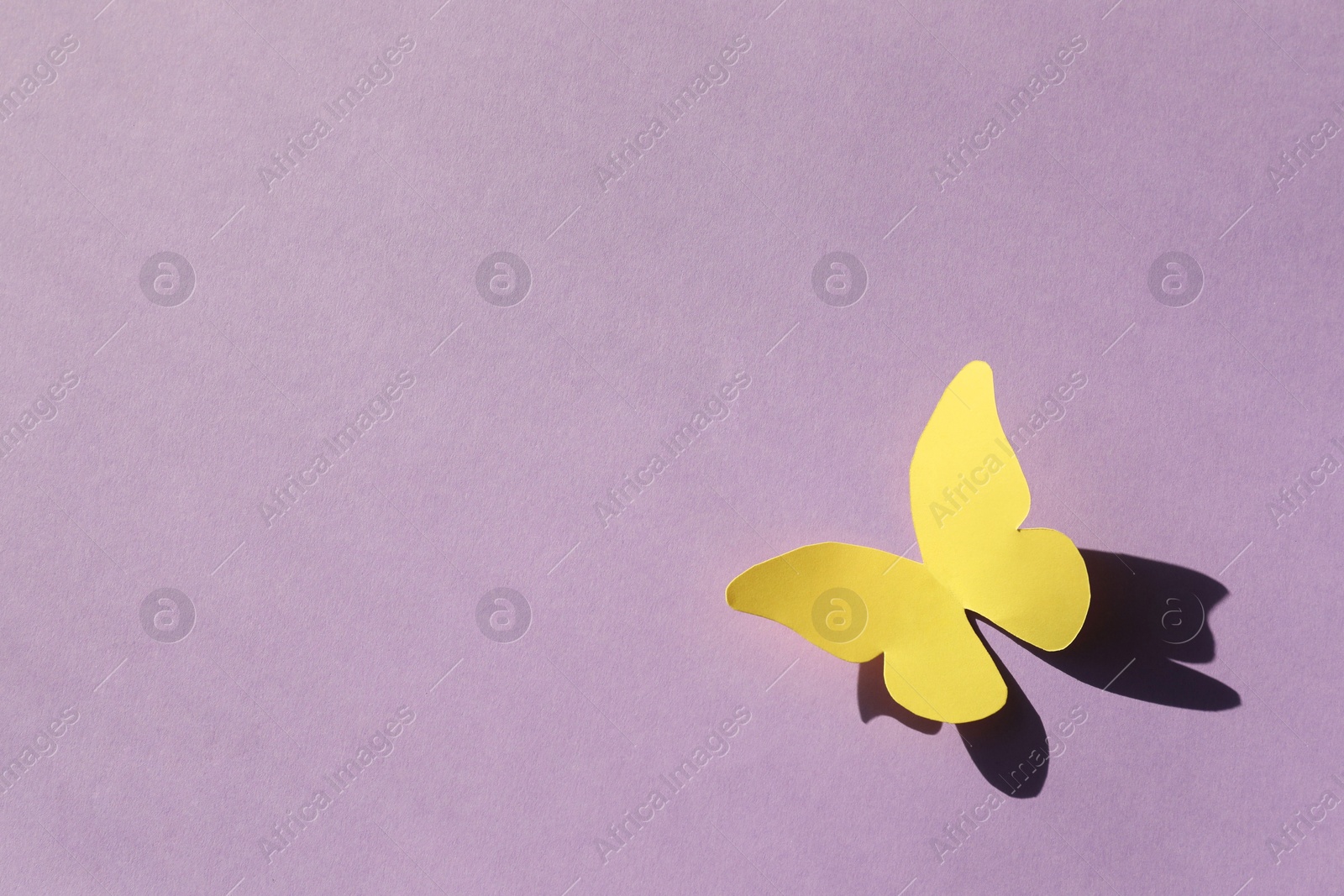 Photo of Yellow paper butterfly on violet background, top view. Space for text