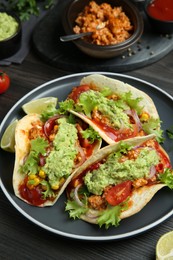Photo of Delicious tacos with guacamole, meat and vegetables on wooden table