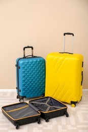 Photo of Modern suitcases on floor near light wall. Travelling preparations