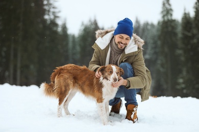 Man with cute dog near forest. Winter vacation