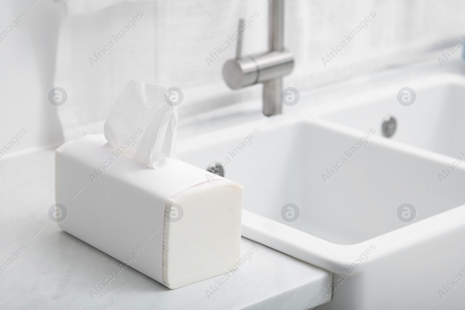 Photo of Package of paper towels on white countertop near sink in kitchen. Space for text