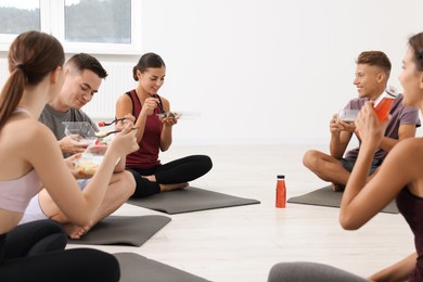 Group of people eating healthy food after yoga class indoors
