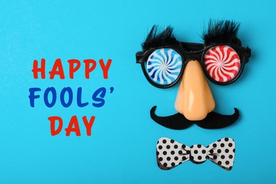 Image of Funny party glasses on light blue background, flat lay. Happy Fool's Day