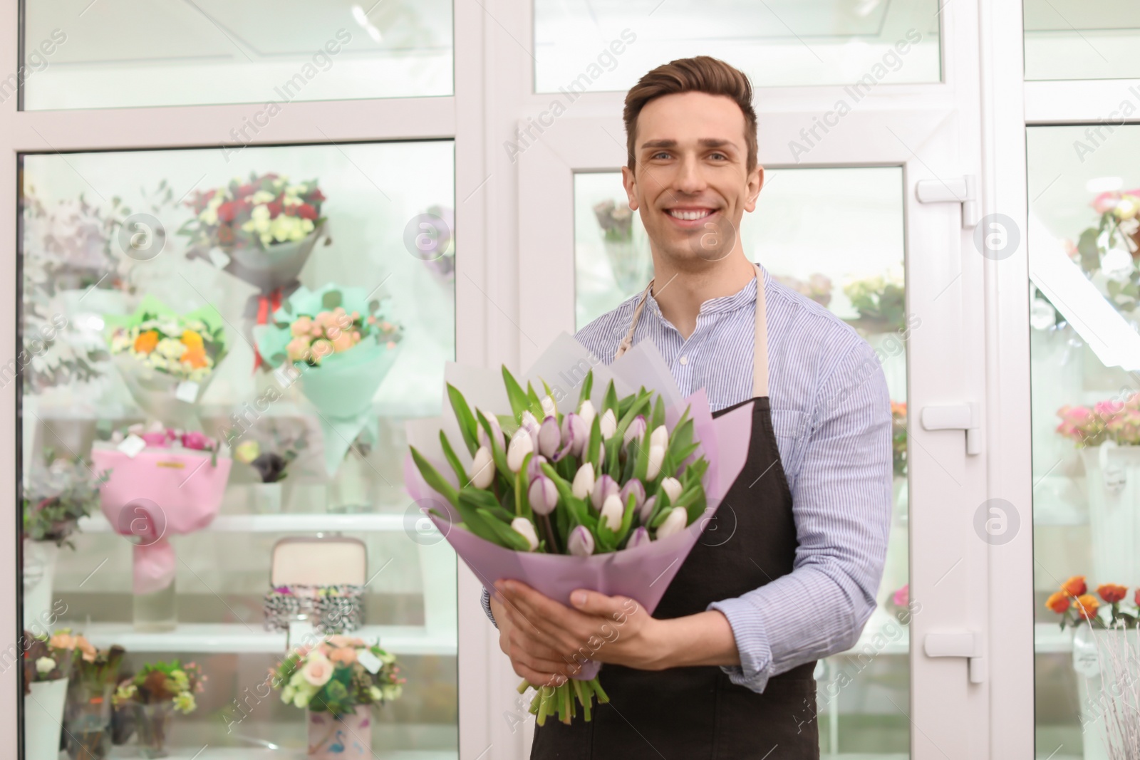 Photo of Male florist holding bouquet flowers at workplace