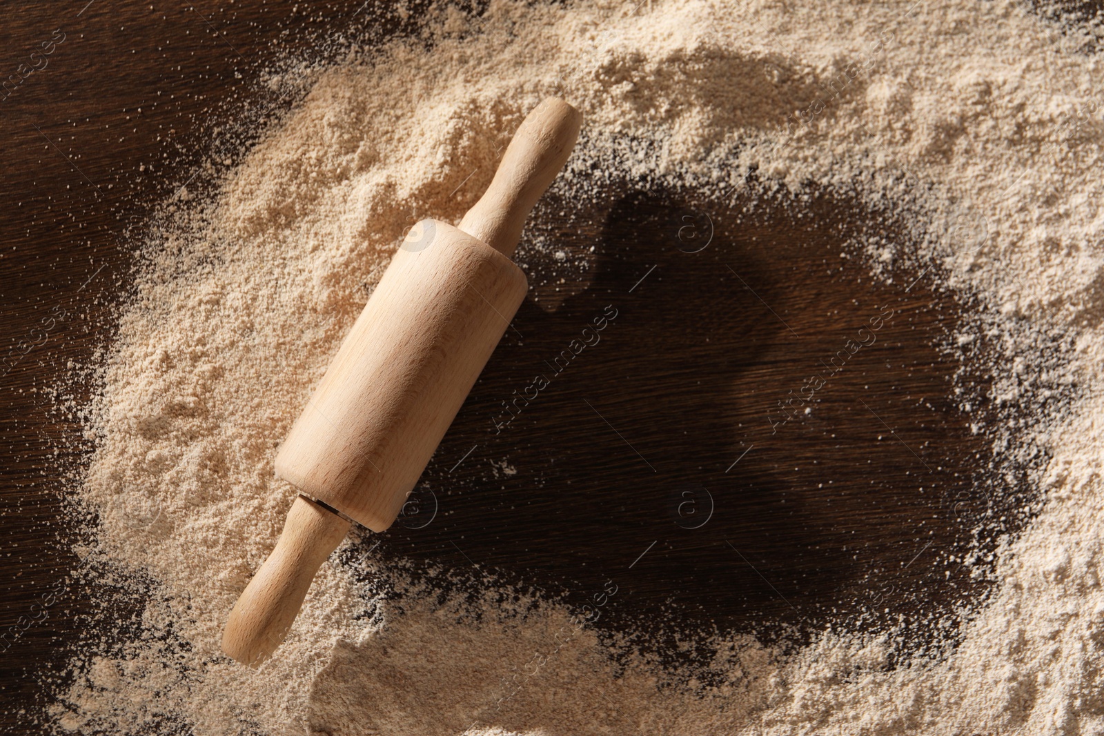 Photo of Frame of flour and rolling pin on wooden table, top view. Space for text