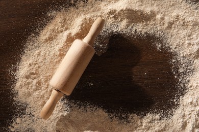 Photo of Frame of flour and rolling pin on wooden table, top view. Space for text