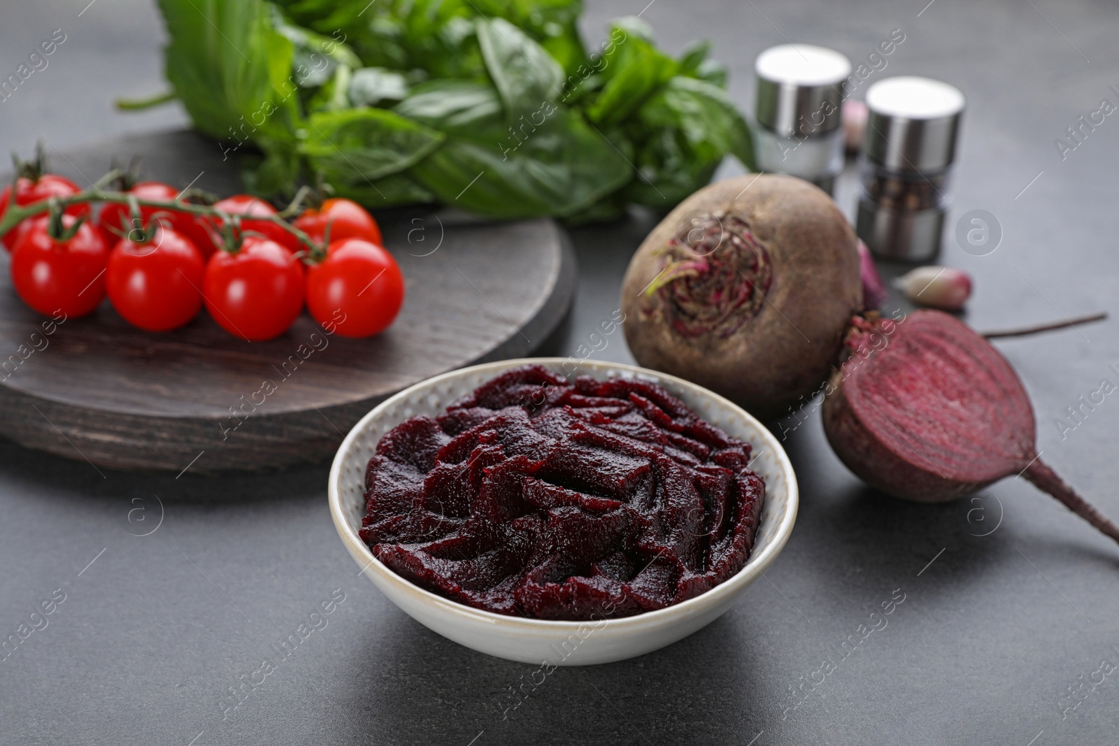 Photo of Bowl with tasty beet puree and ingredients on black table