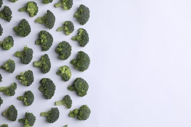 Photo of Many fresh green broccoli pieces on white background, flat lay. Space for text