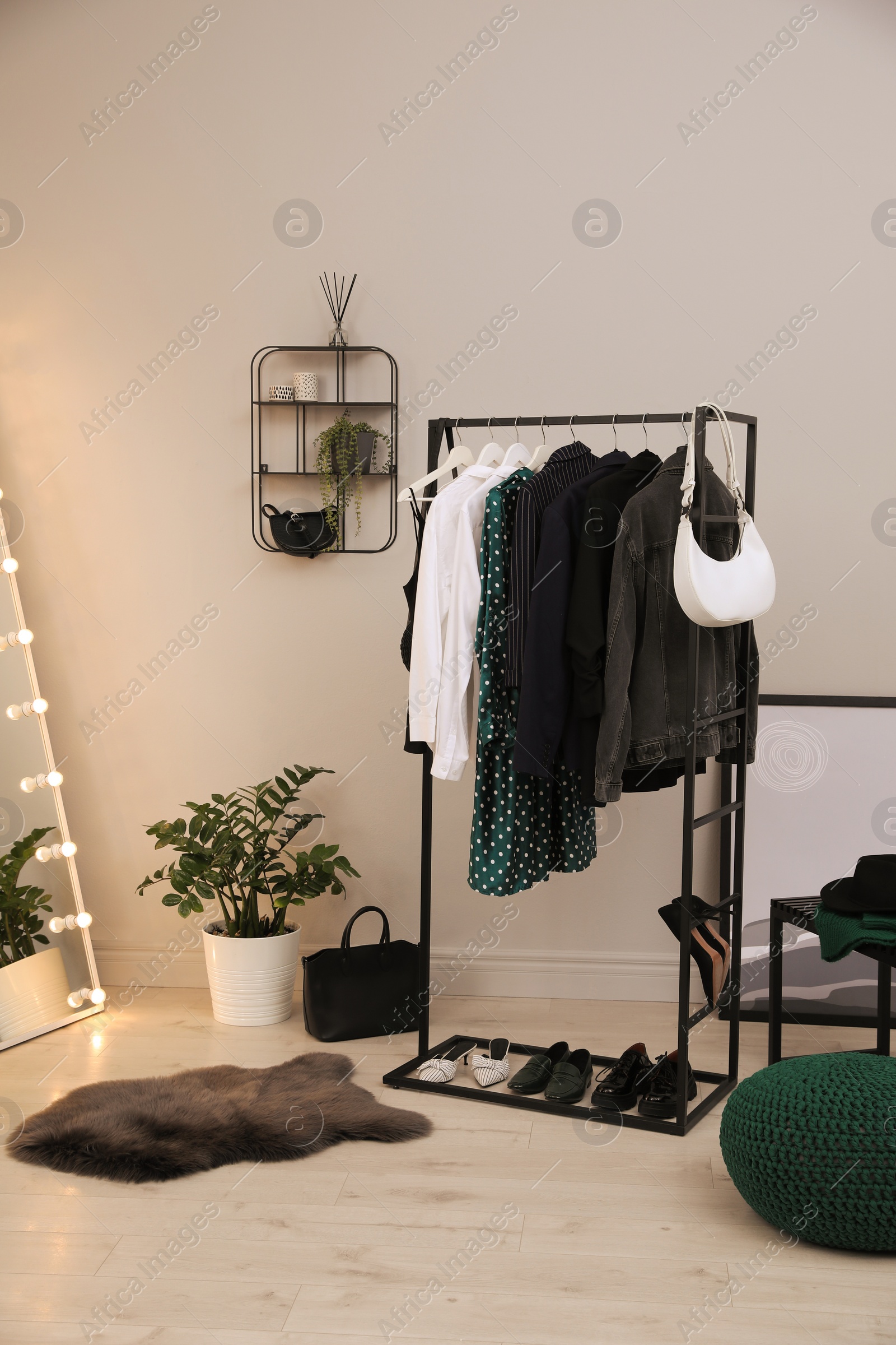 Photo of Rack with stylish women's clothes and shoes in dressing room