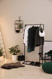 Rack with stylish women's clothes and shoes in dressing room