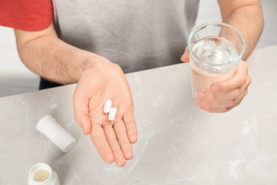 Young man taking pills at table at table