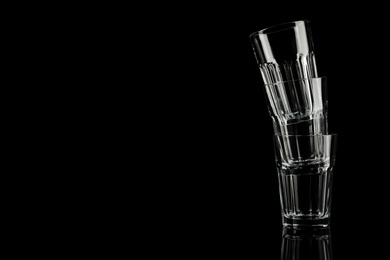 Photo of Stack of empty glasses on black background. Space for text
