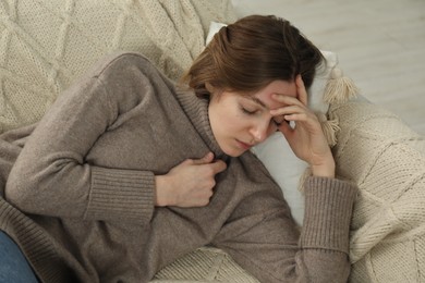 Photo of Sad young woman lying on sofa indoors