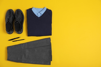 Photo of Flat lay composition with school uniform on yellow background. Space for text