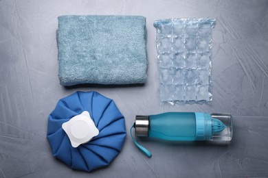 Photo of Bottle of water, cold compress, ice pack and towel on grey background, flat lay. Heat stroke treatment