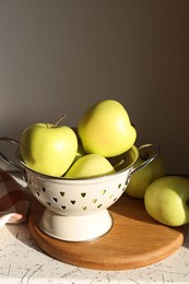 Photo of Fresh apples in colander on white table