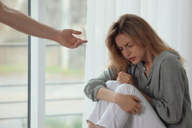 Photo of Man offering hand to depressed woman indoors