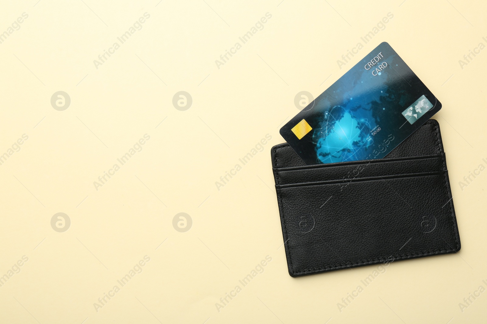 Photo of Leather card holder with credit card on beige background, top view. Space for text