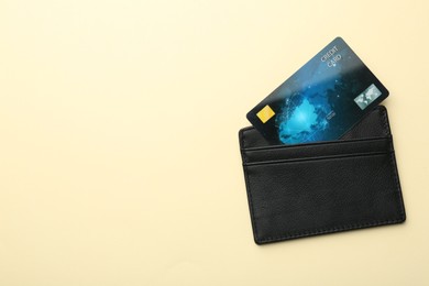 Photo of Leather card holder with credit card on beige background, top view. Space for text