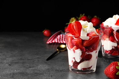 Photo of Delicious strawberries with whipped cream served on grey table. Space for text