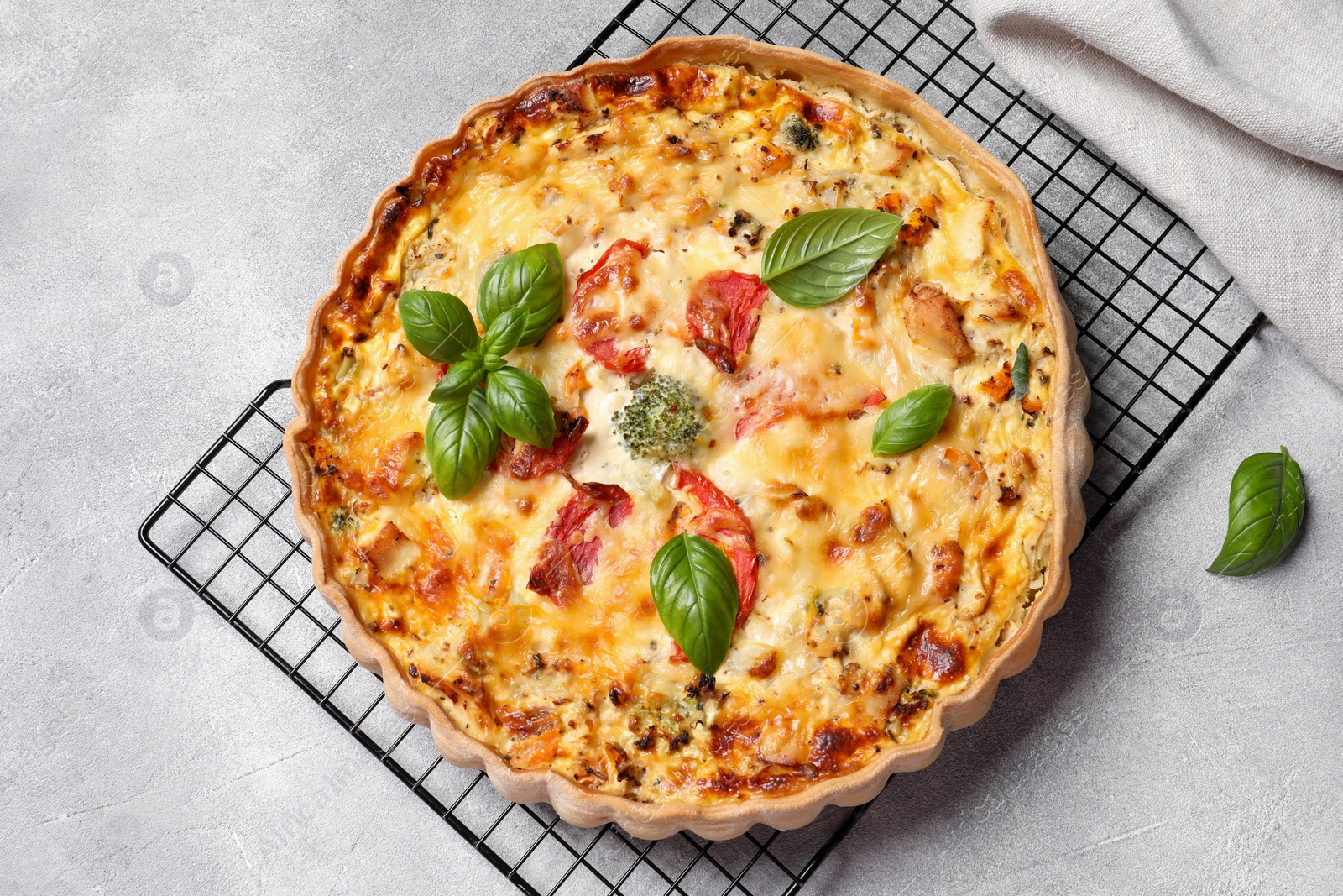 Photo of Tasty quiche with tomatoes, basil and cheese on light textured table, flat lay