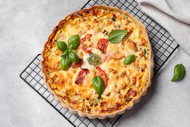Tasty quiche with tomatoes, basil and cheese on light textured table, flat lay