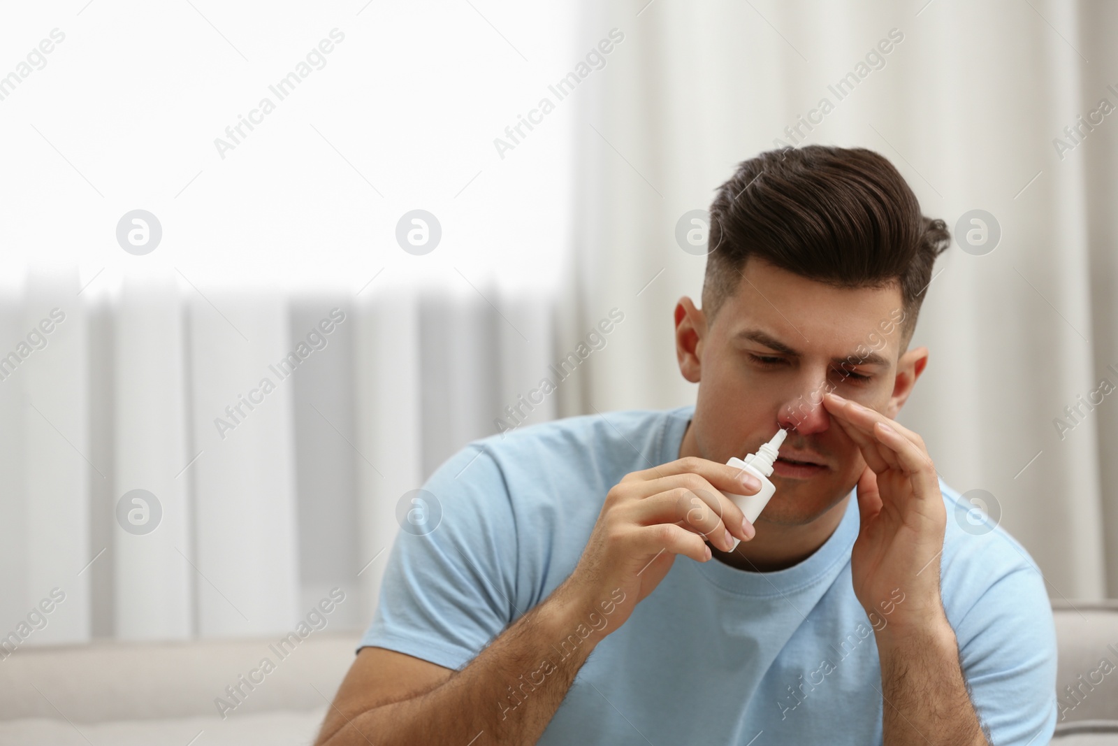 Photo of Ill man using nasal spray at home