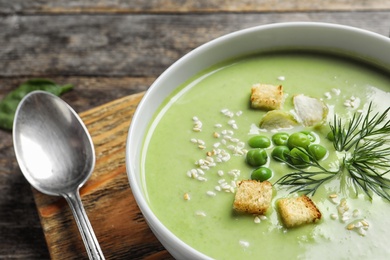 Photo of Fresh vegetable detox soup made of green peas with croutons in dish on table, closeup