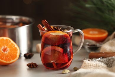 Photo of Glass cup of tasty mulled wine on grey table