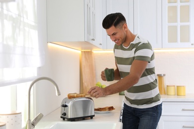 Photo of Man using modern toaster at kitchen counter