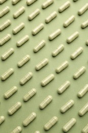 Vitamin capsules on olive background, flat lay