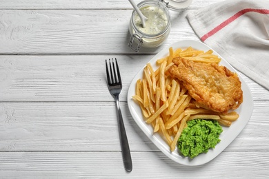 Photo of Plate with British traditional fish and potato chips on wooden background, top view. Space for text