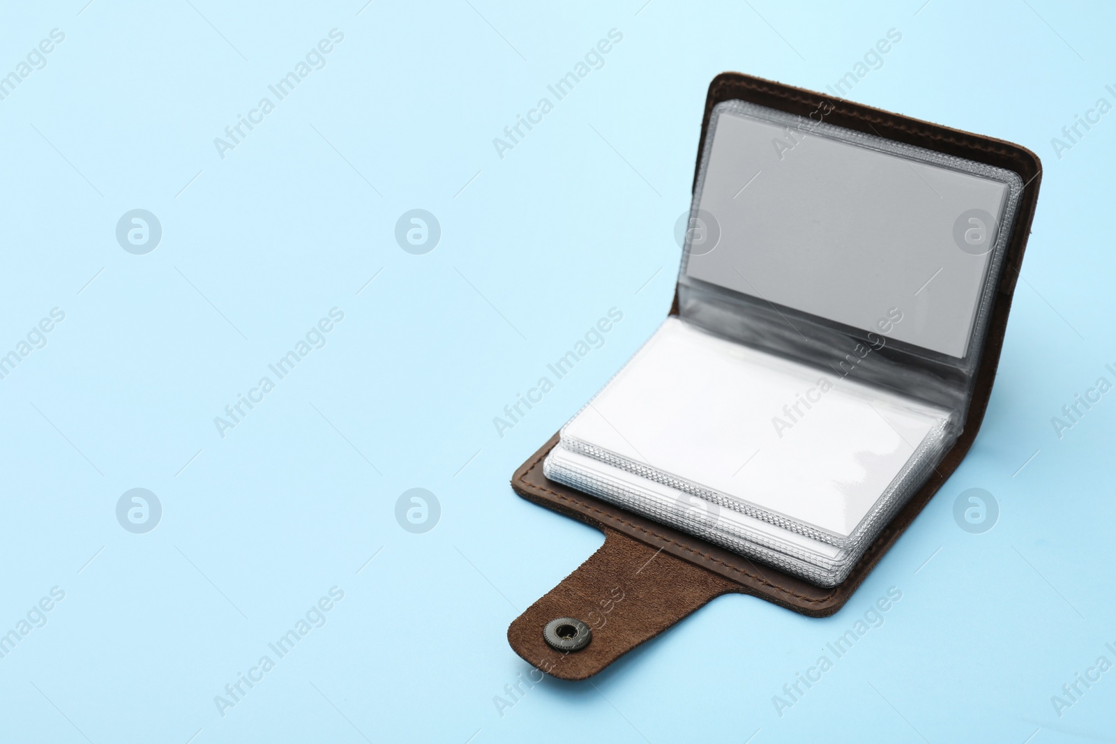 Photo of Leather business card holder with blank cards on light blue background. Space for text