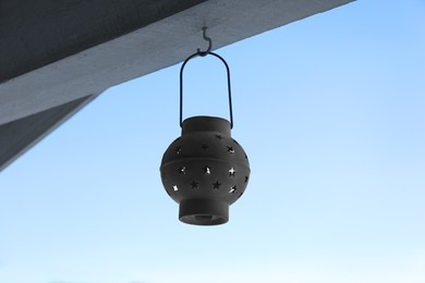 Photo of Stylish lantern hanging against blue sky outdoors