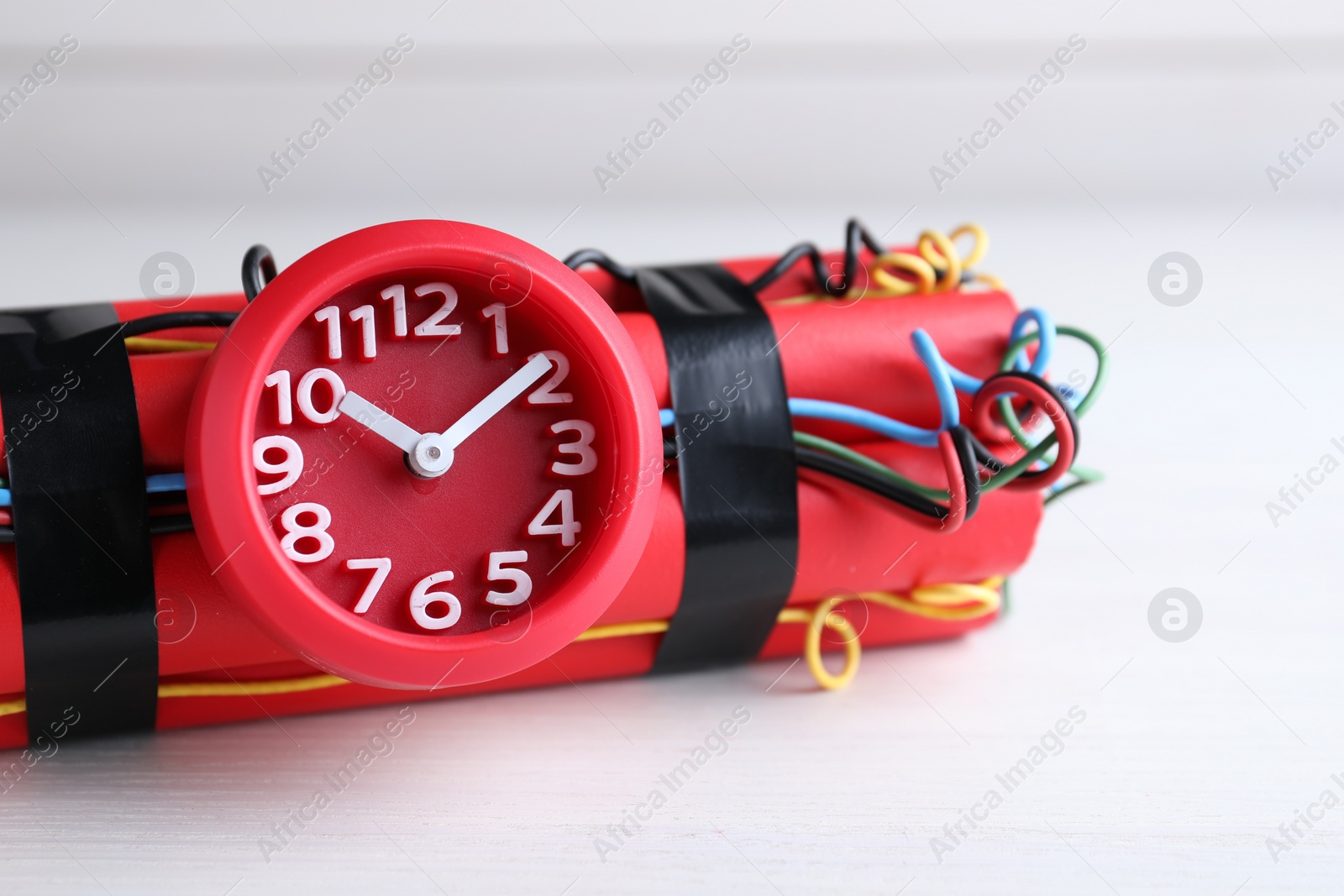 Photo of Explosive dynamite time bomb on white wooden background