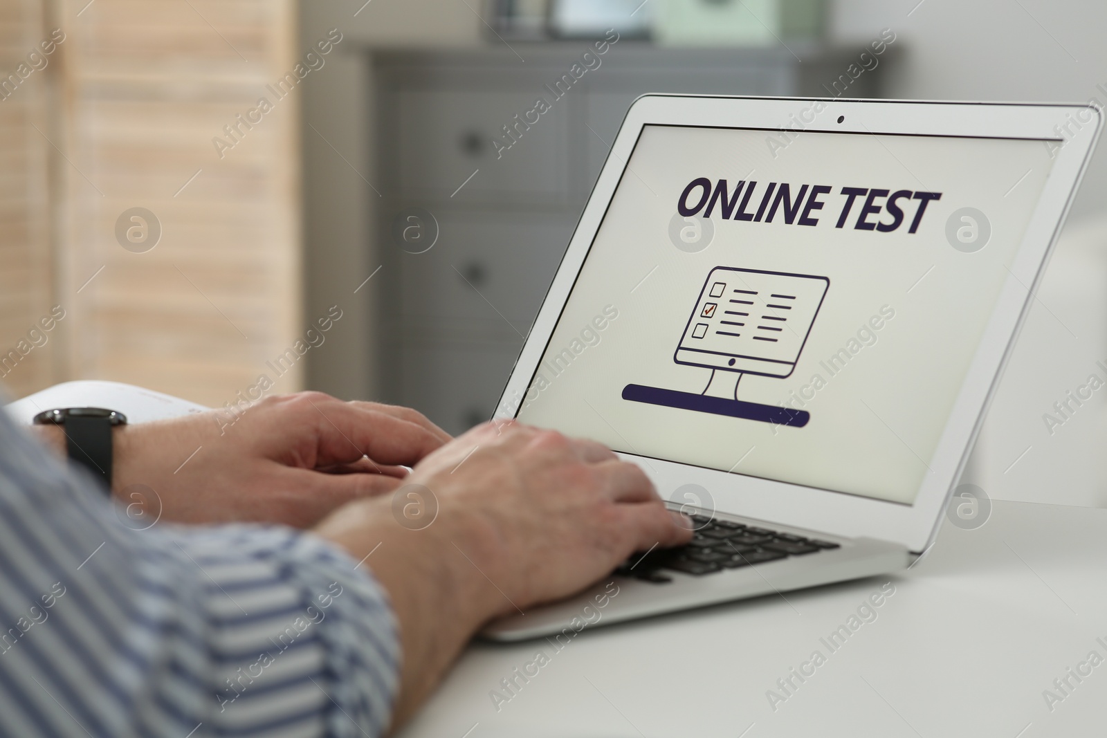 Photo of Man taking online test on laptop at desk indoors, closeup