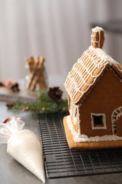 Beautiful gingerbread house decorated with icing on grey table