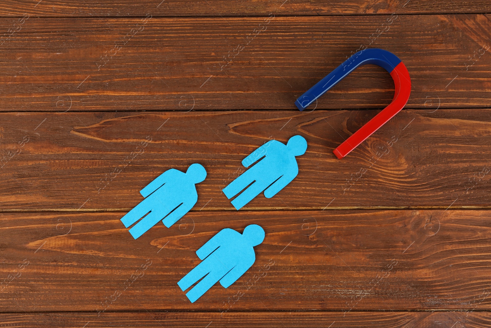 Photo of Magnet and paper people on wooden table, flat lay