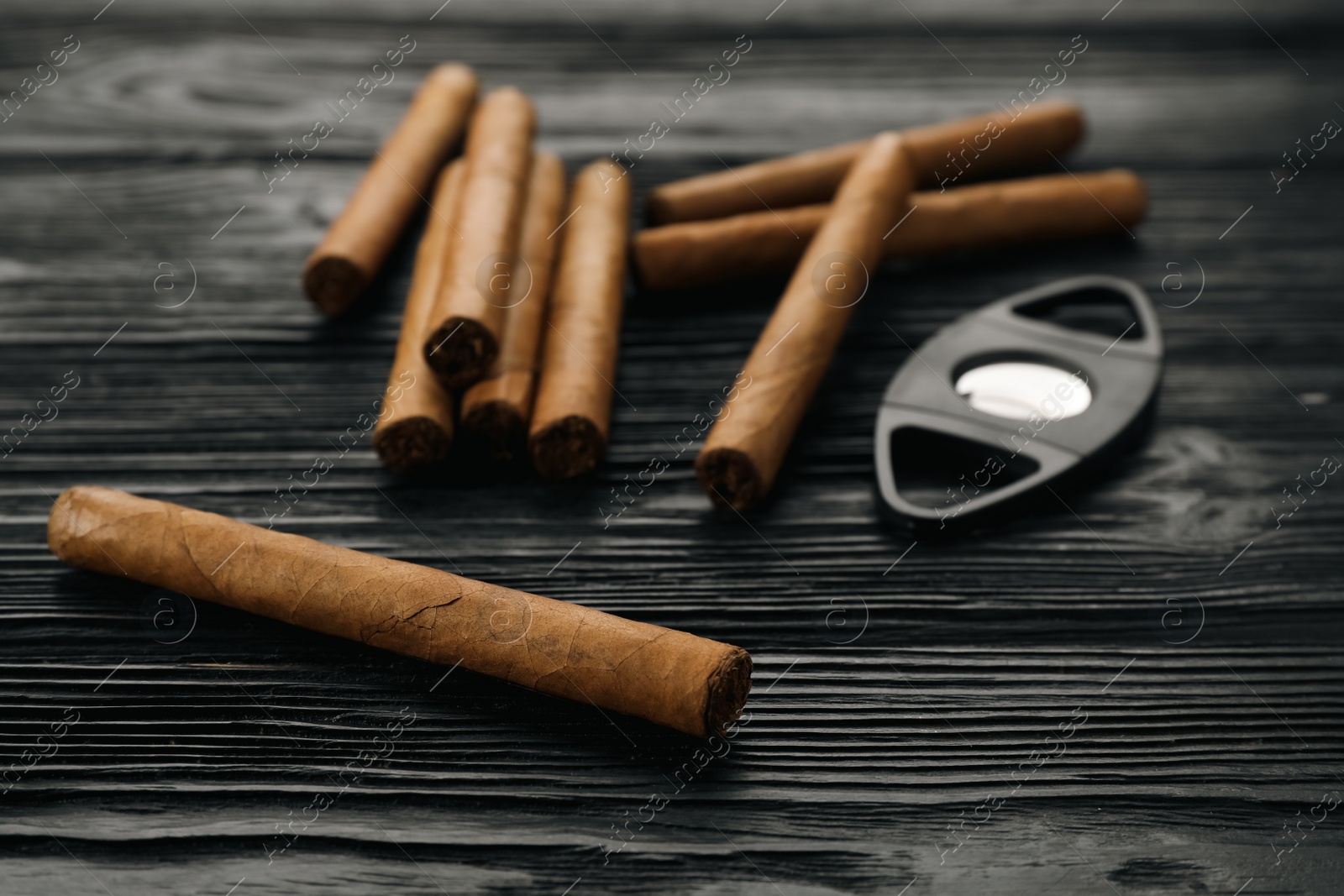 Photo of Cigars and guillotine cutter on black wooden table