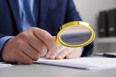 Photo of Man looking at document through magnifier at white table, closeup. Searching concept