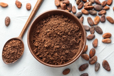 Flat lay composition with cocoa powder and beans on light background