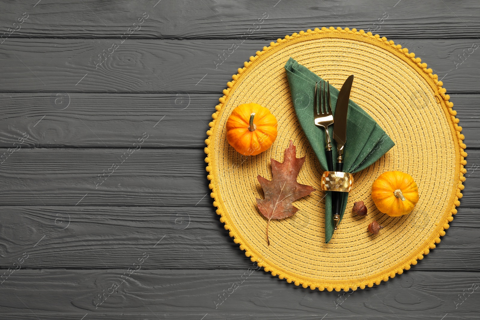 Photo of Cutlery, napkin and pumpkins on gray wooden background, flat lay with space for text. Table setting