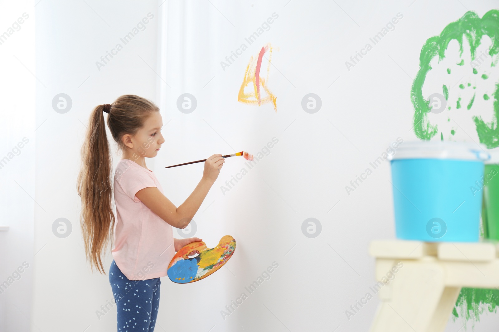 Photo of Little child painting on white wall indoors