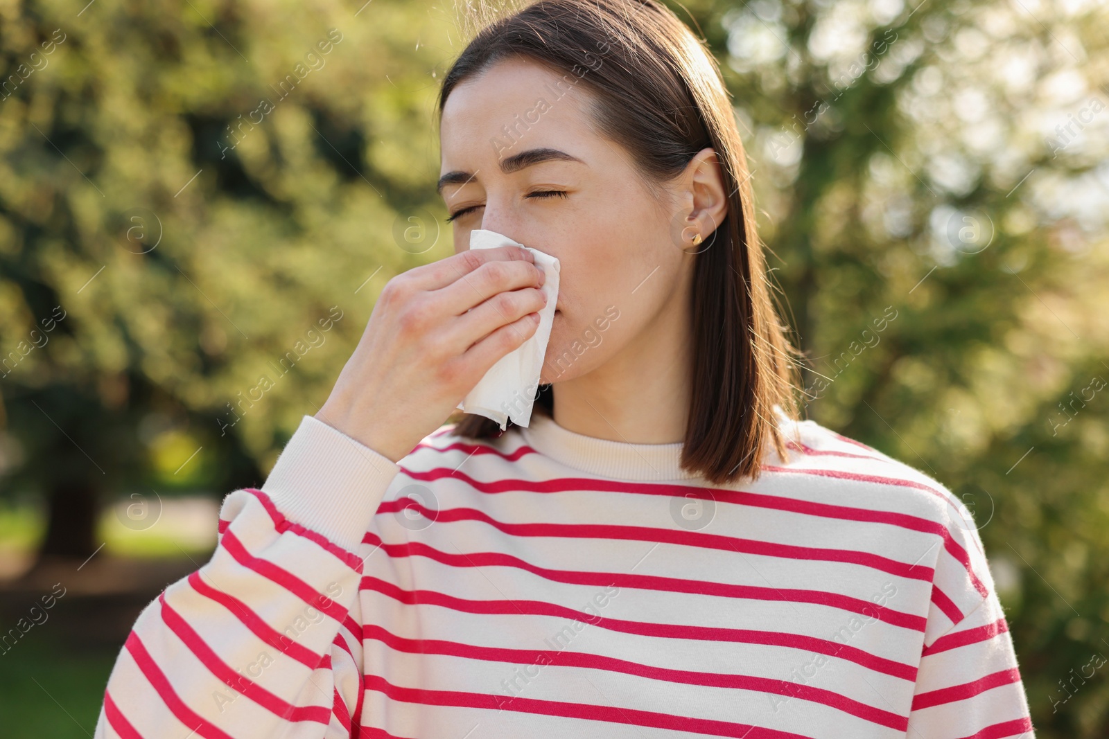 Photo of Woman with napkin suffering from seasonal allergy outdoors