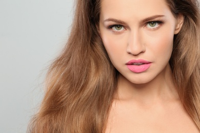 Young woman wearing beautiful lipstick on gray background