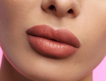 Image of Woman with beautiful perfect lips after permanent makeup procedure on pink background, closeup