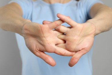 Photo of Woman cracking her knuckles on light grey background, closeup. Bad habit